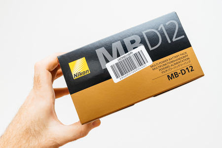 PARIS, FRANCE - FEB 5, 2018: Photographer hand holding against white background a box with Nikon MB-D12 camera grip for the Nikon D810 D800 professional DSLR camera front viewのeditorial素材