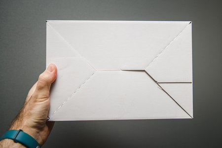 Crop male hand with white blank carton box on gray backgroundの写真素材