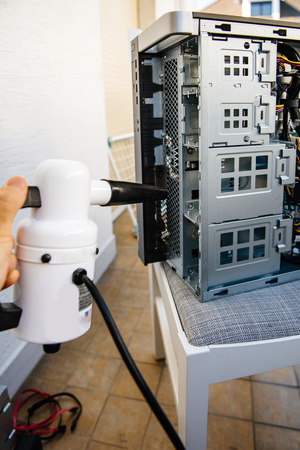 Side view of man hand holding vacuum pump to clean computer case on balconyの写真素材