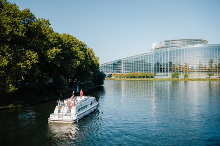 STRASBOURG, FRANCE - SEP 12, 2018: Le Boat travels on the Ill river canal in front of European parliament building in Strasbourgのeditorial素材
