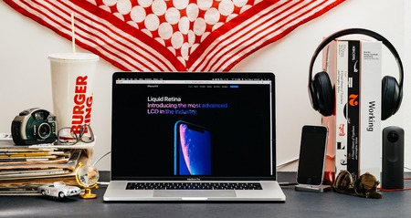 LONDON, UK - SEP 13, 2018: Creative room table with Safari Browser on MacBook Pro laptop showcasing Apple Computers website latest iPhone Xr smartphone with liquid retina displayのeditorial素材