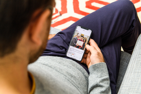 LONDON, UK - SEP 21, 2018: Man using the new Apple iPhone Xs with the immense OLED retina display and a12 bionic chip, looking over the app application Mark Zuckerberg getting degree with his parents instagram postのeditorial素材