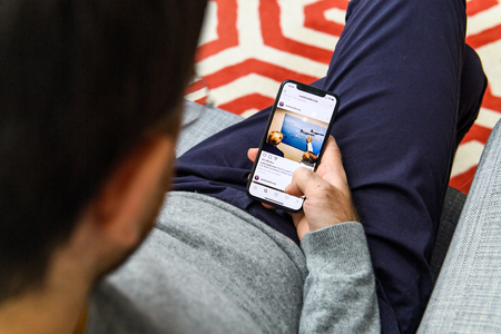 LONDON, UK - SEP 21, 2018: Man using the new Apple iPhone Xs with the immense OLED retina display and a12 bionic chip, looking over the app application Real Donald Trump profile appのeditorial素材
