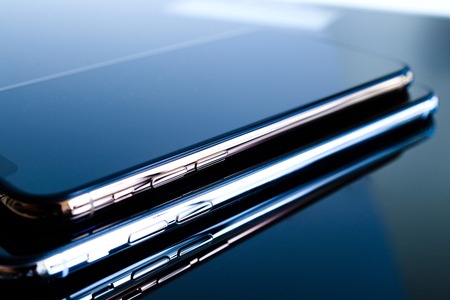 PARIS, FRANCE - SEP 25, 2018: One above another iPhone Xs and Xs Max smartphone model by Apple Computers close up of newest golden iPhone mobile phone device on technology blue reflective backgroundのeditorial素材