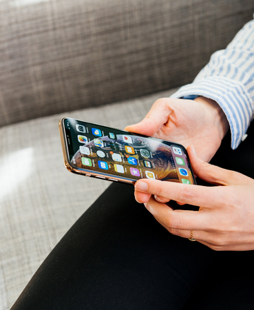 PARIS, FRANCE - SEP 27, 2018: Detail of hands testing the newest latest iPhone Xs and Xs Max smartphone telephone from Apple Computers on office living room sofaのeditorial素材