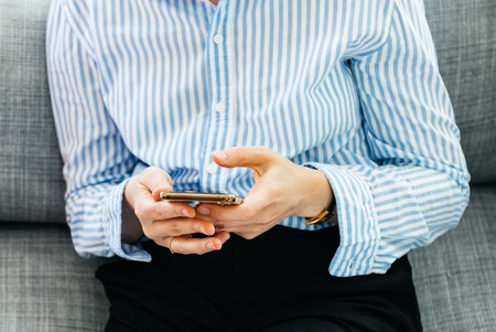 PARIS, FRANCE - SEP 27, 2018: Detail of elegant woman testing the newest latest iPhone Xs and Xs Max smartphone telephone from Apple Computers on office living room sofa texting social network communicaitonのeditorial素材