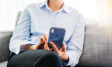 PARIS, FRANCE - SEP 27, 2018: Elegant business woman unboxing silicone protection case for her latest iPhone Xs and Xs Max smartphone telephone from Apple Computers on office living room sofaのeditorial素材