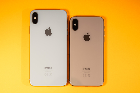 PARIS, FRANCE - SEP 27, 2018: Compare Apple Computers iPhone Xs and Xs Max as hero object on bright glamorous modern neon pop orange background - smartphone telephone Apple icon glass backのeditorial素材