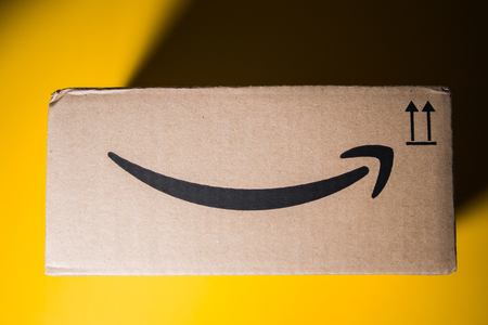 PARIS, FRANCE - SEP 28, 2018: Directly above view of New Amazon Cardboard box against yellow background. Amazon Prime is the online paid subscription service offered by Amazon.com web-commerce siteのeditorial素材
