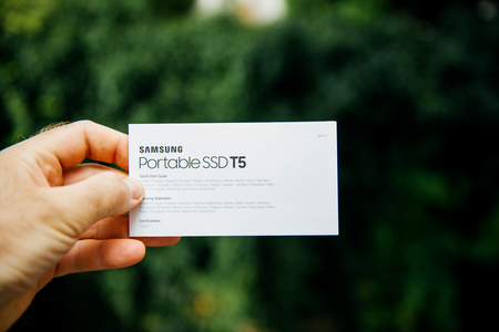 PARIS, FRANCE - AUG 14, 2018: Man hand holding quick start quide of Samsung T5 Portable SSD 2 tb external hard drive disk with high read and write speed against green background unboxing testingのeditorial素材