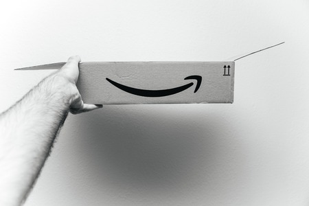 PARIS, FRANCE - AUG 11, 2018: Man holding against white background Amazon Prime cardboard box after the unboxing showing the open box - black and whiteのeditorial素材