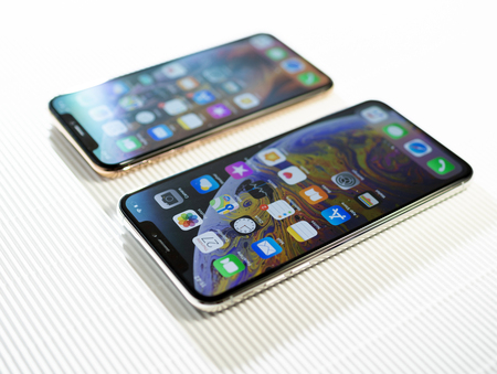 PARIS, FRANCE - SEP 27, 2018: Tilt-shift focus lens over two new Apple Computers iPhone Xs and Xs Max with home apps on the gorgeous OLED display on stripe cardboard background - side viewのeditorial素材