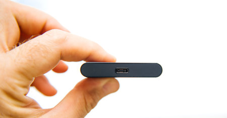 Man hand holding portable SSD 2 tb external hard drive disk with high read and write speed against...