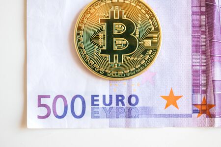 LONDON, UNITED KINGDOM - MAR 30, 2014: Golden Bitcoin on five hundred euro currency note - directly above viewのeditorial素材