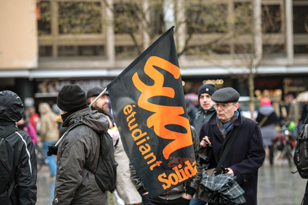 STRASBOURG, FRANCE - MAR 22, 2018: People gathering in Place Kleber square during CGT General Confederation of Labour demonstration protest against Macron French government string of reforms - man with student association flag STRASBOURG, FRANCE - MAR 22, 2018: People gathering in Place Kleber square during CGT General Confederation of Labour demonstration protest against Macron French government string of reforms - man with student association flag
