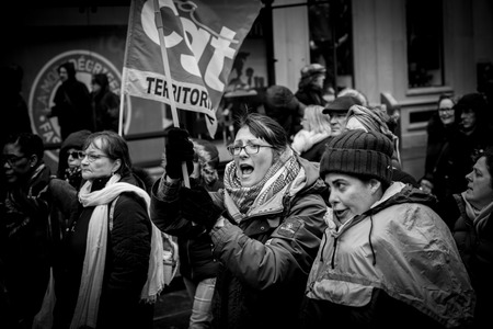 STRASBOURG, FRANCE - MAR 22, 2018: Young woman proteting holding CGT General Confederation of Labour flag with other  workers holding placards at demonstration protest against Macron French government string of reforms - black na dwhiteのeditorial素材