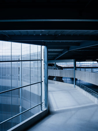 Blue color cast over modern generic airport parking with spiral central acces path