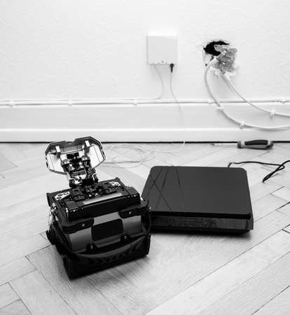 FTTH fiber installation at home with new arc clad-alignment fusion splicer used for splicing an array of thin optical fiber types with CATV on wall socket and tv internet receiver tuner black and whiteの写真素材