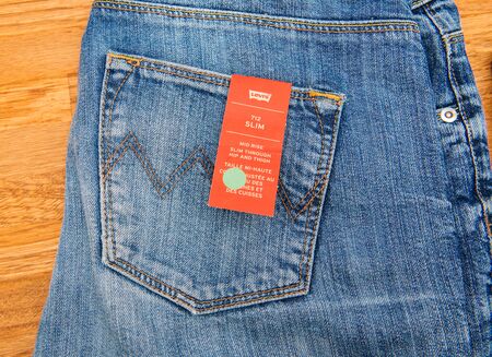 PARIS, FRANCE - JAN 2, 2018: New Jeans with price tag manufactured by the Levis placed on natural wooden table - model Vintage Soft Slimのeditorial素材