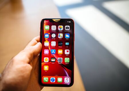 STRASBOURG, FRANCE - OCT 26, 2018: Customer POV holding new red iPhone XR smartphone during the launch day admiring all home apps screenのeditorial素材