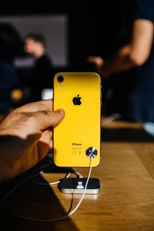 STRASBOURG, FRANCE - OCT 26, 2018: Customer POV holding new yellow iPhone XR smartphone rear view in Apple Store Computers during the launch day admiring the yellow glass with logo customers backgroundのeditorial素材