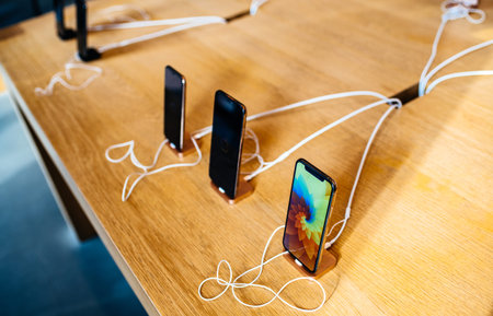 PARIS, FRANCE - OCT 26, 2018: Latest iPhone Xs smartphone in Apple Store Computers in a row charging