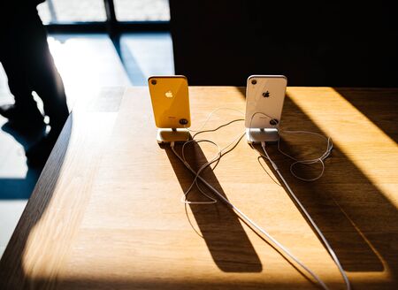 PARIS, FRANCE - OCT 26, 2018: View from above of yellow and white new iPhone XR smartphone in Apple Store Computers during the launch day with long shadow on wooden table horizontal imageのeditorial素材