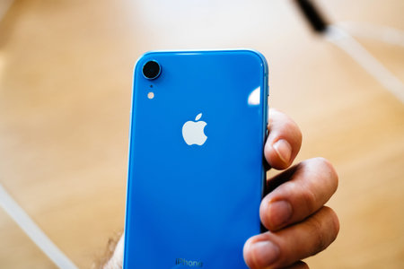 PARIS, FRANCE - OCT 26, 2018: man hand holding latest blue iPhone XR smartphone in Apple Store...