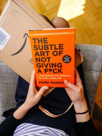 PARIS, FRANCE - OCT 4, 2018: View from above of woman unboxing new bookdelivered by Amazon The Subtle art of not giving a fuck byのeditorial素材