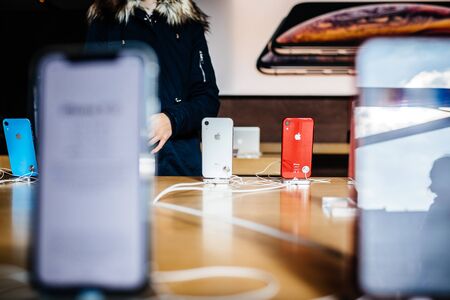 PARIS, FRANCE - OCT 26, 2018: Latest iPhone XR smartphone in Apple Store Computers during the launch day- view of red phone in docking stationのeditorial素材