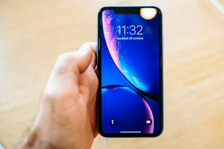 PARIS, FRANCE - OCT 26, 2018: man hand holding latest blue iPhone XR smartphone in Apple Store...