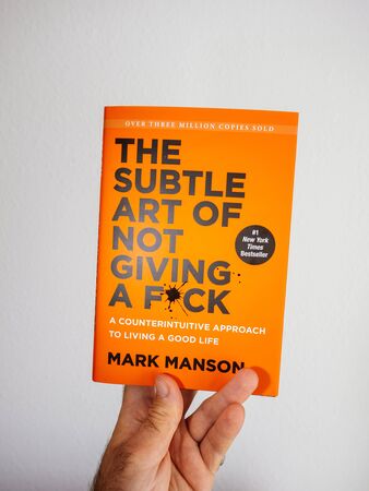 PARIS, FRANCE - OCT 4, 2018: Man holding new book against white background The Subtle art of not giving a fuck by Mark Mansonのeditorial素材