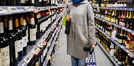STRASBOURG, FRANCE - DEC 30, 2017: Elegant unrecognizable French woman buying diverse alcoholic drinks wines, champagne and whiskey in wine department of a large French supermarketのeditorial素材