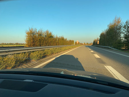Car shadow on German autobahn asphalt driving fast at sunset - colorful sunset
