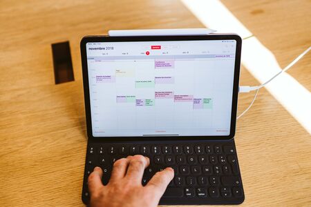 PARIS, FRANCE - NOV 7, 2018: Customer POV personal perspective experiencing new Apple iPad Pro with Face ID, A12X Bionic with Neural Engine and thin completely redesigned body using calendar appのeditorial素材