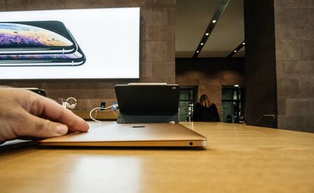 PARIS, FRANCE - NOV 8, 2018: Man touching the closed side view new Apple MacBook Air thin laptop featuring Retina screen and new CPU - Apple Store view with customers in backgroundのeditorial素材