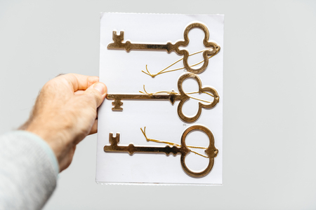 Man holding against white background a set of three vintage ancient gold keys - vertical holdingの写真素材