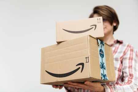 PARIS, FRANCE - DEC 2, 2018: Woman hiding behind two Amazon Prime parcel cardboard box stack one above another ready for winter holidays gifts shoppingのeditorial素材