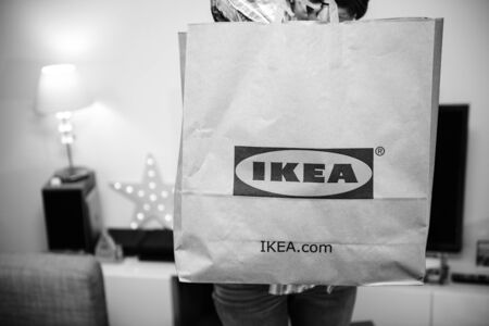 PARIS, FRANCE - DEC 2, 2018: Elegant French woman holding big paper IKEA bag full with merchandise from the famous swedish furniture retailer - black and whiteのeditorial素材