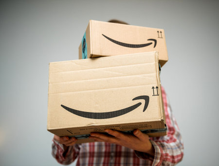 PARIS, FRANCE - DEC 2, 2018: Casual dressed woman holding two freshly received Amazon Prime parcel...