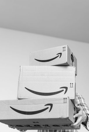 PARIS, FRANCE - DEC 2, 2018: Casual dressed woman holding three Amazon Prime parcel cardboard box...