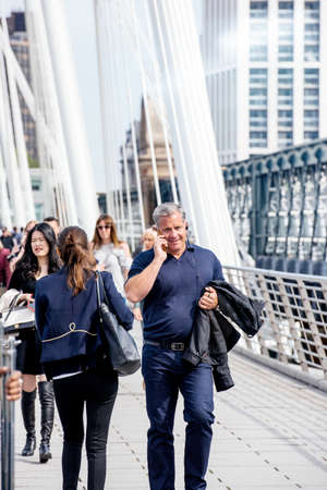 LONDON, UNITED KINGDOM - MAY 18, 2018: Pedestrians walking on a warm sunny day on the Hungerford Bridge in Londonのeditorial素材