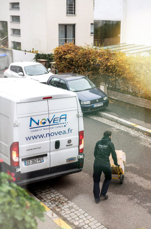 Paris, France - Nov 14, 2018: Man pushing carriage trolley from delivery truck merchandise for delivery in the office home - elevated viewのeditorial素材