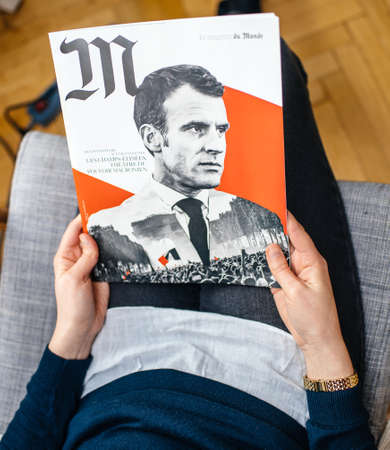 Paris, France - Jan 2, 2019: Woman reading M le magazine du monde with controversial cover featuring French presidient Emmanuel Macron with a photo collage of Macron and the Yellow Vest protestersのeditorial素材