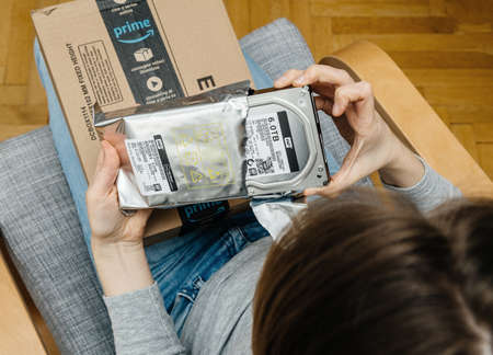PARIS, FRANCE - NOV 4, 2017: Woman POV unboxing on the living room armchair the Amazon Prime cardboard box with Western Digital 6 terabyte HDD hard disk driveのeditorial素材