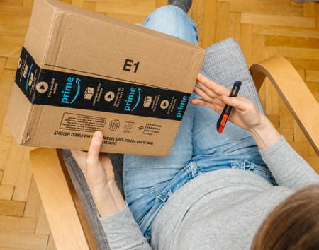 PARIS, FRANCE - NOV 4, 2017: Woman holding cutter preparing to unbox the Amazon Prime large cardboard box with Prime sealing tapeのeditorial素材