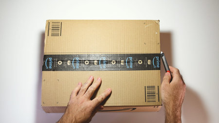 Paris, France - Feb 20, 2019: View from above of man hands unpacking new Amazon Prime cardboard box...