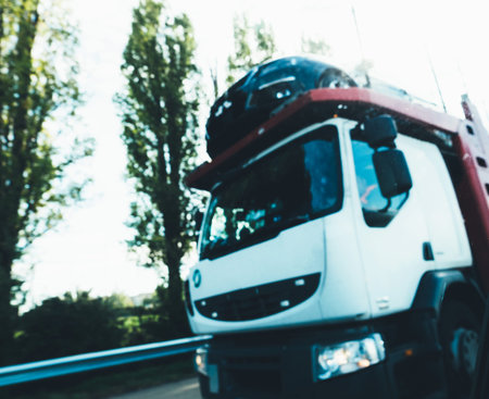 Defocused view of white truck transporting multiple cars on German highway