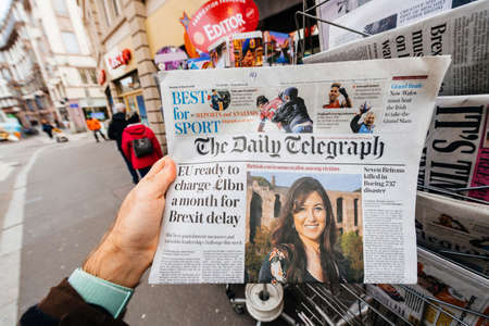 Paris, France - Mar 12, 2019: Man buying press kiosk British newspaper The Daily Telegraph featuring on the cover text that Eu ready to charge 1 billion a month for Brexit delayのeditorial素材