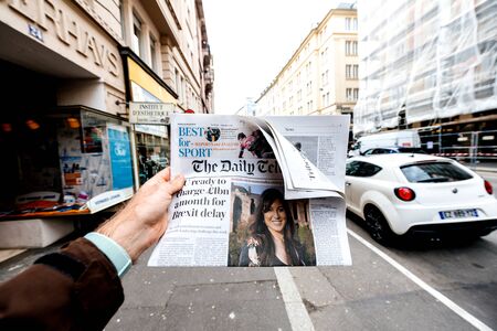 Paris, France - Mar 12, 2019: Man holding British newspaper The Daily Telegraph featuring on the cover text that Eu ready to charge 1 billion a month for Brexit delayのeditorial素材